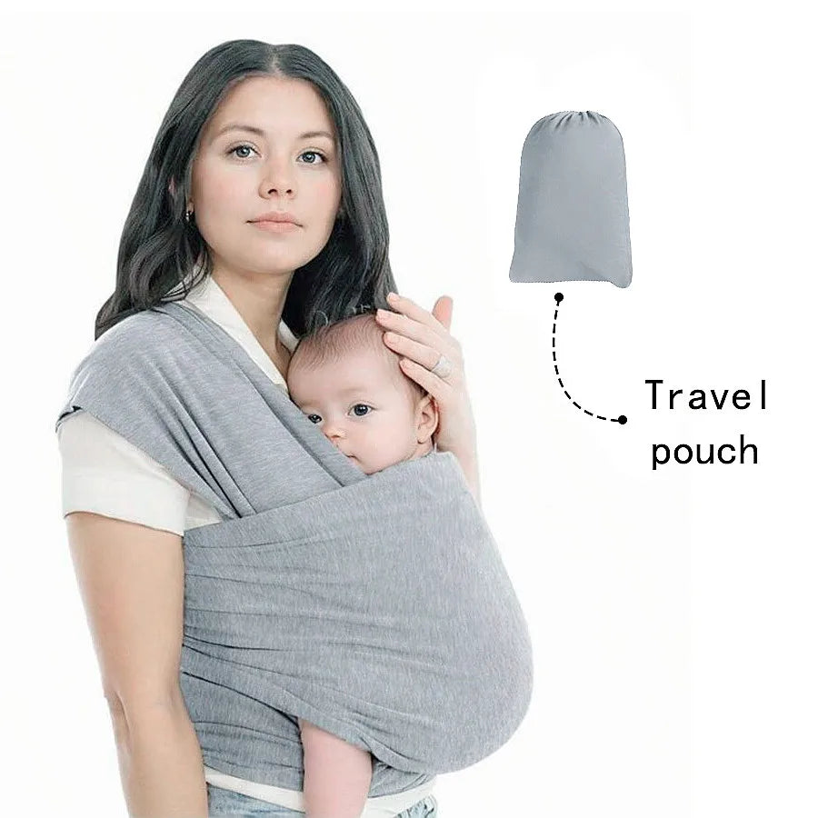 A woman is wearing a grey knitted fabric baby carrier with an attached travel pouch.