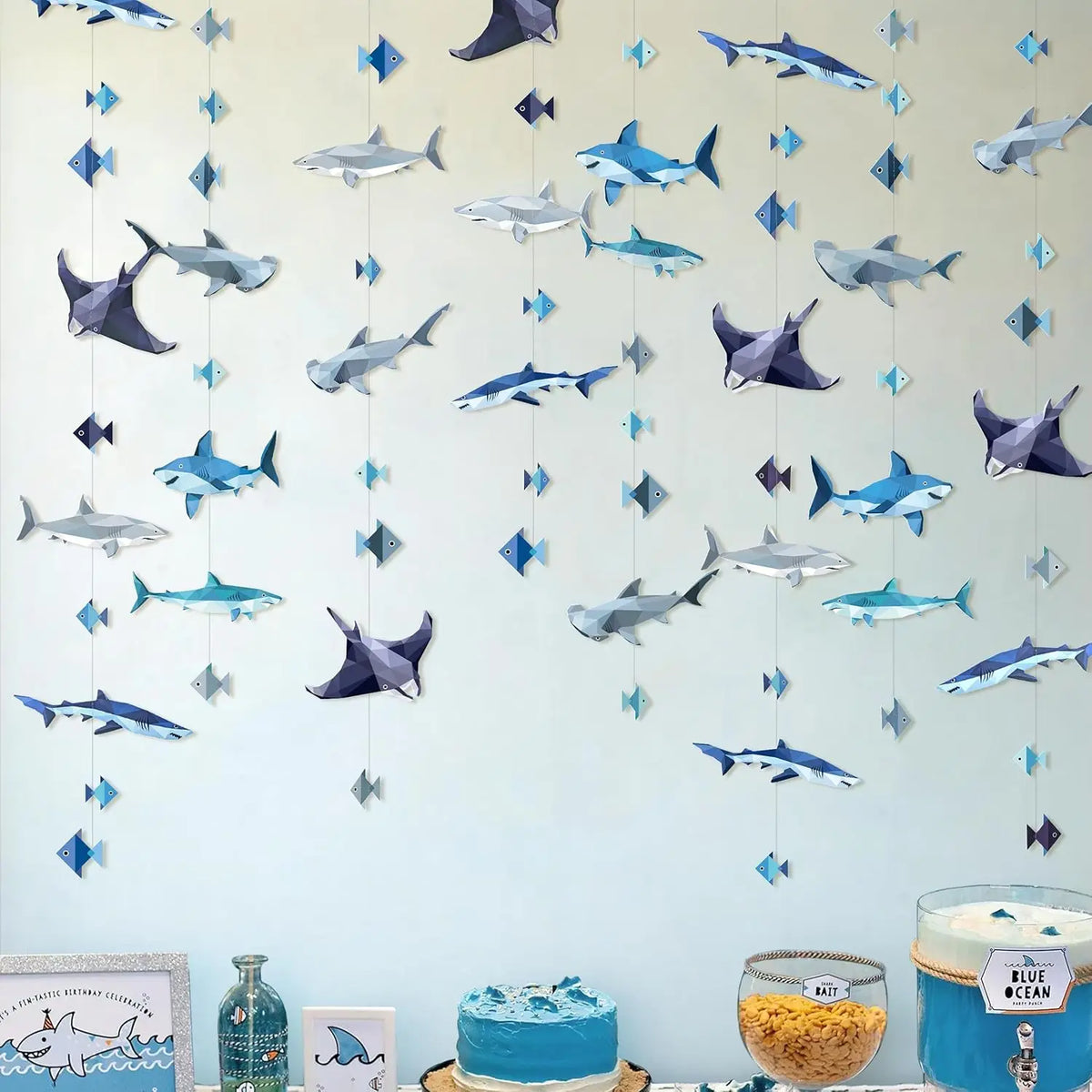 A blue and silver geometric shark banner and hanging garland set displayed against a light blue wall.