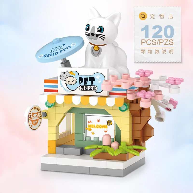 A white cat figurine stands next to a miniature shop building block set featuring a cat theme.