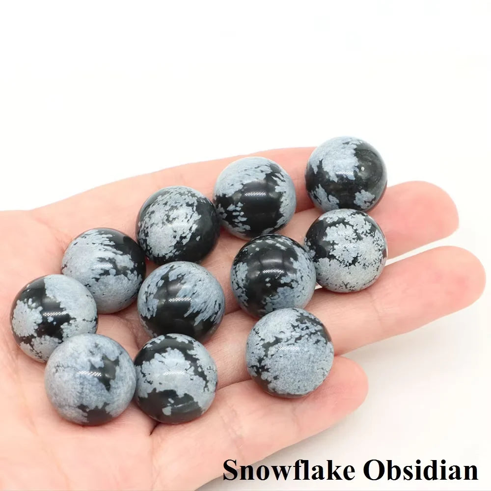 A collection of black and white snowflake obsidian crystal spheres held in a hand.