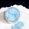A clear jar filled with light blue adhesive flocking powder resting on a white plate.