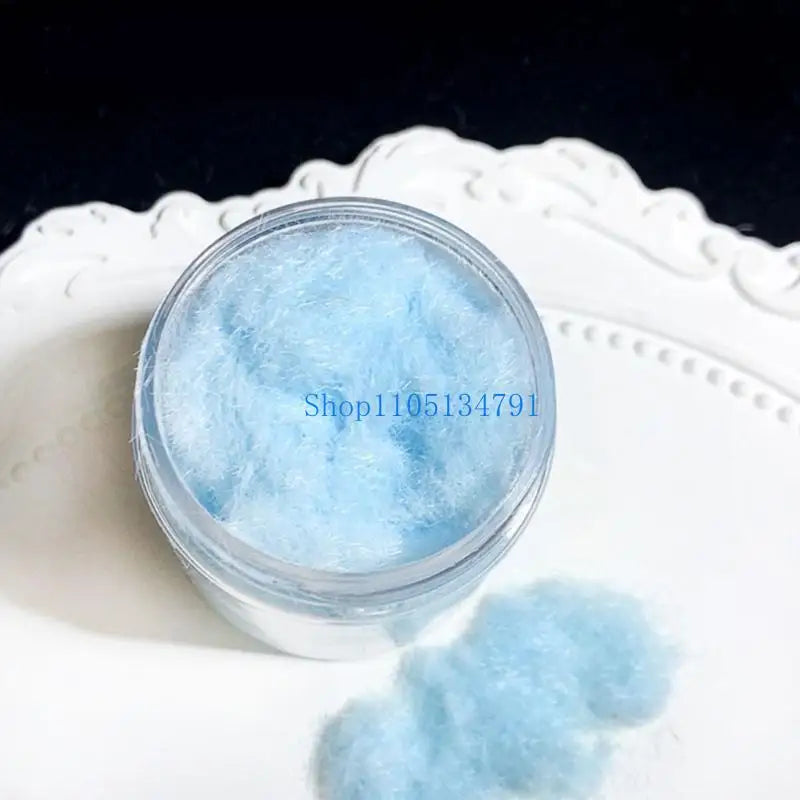 A clear jar filled with light blue adhesive flocking powder resting on a white plate.