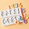 A silicone mold set featuring numbers 1 through 8 in pastel colors like pink, yellow, and blue on a white tray.