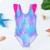 A purple and blue mermaid unicorn one-piece swimsuit with pink ruffled trim lying on a white surface.
