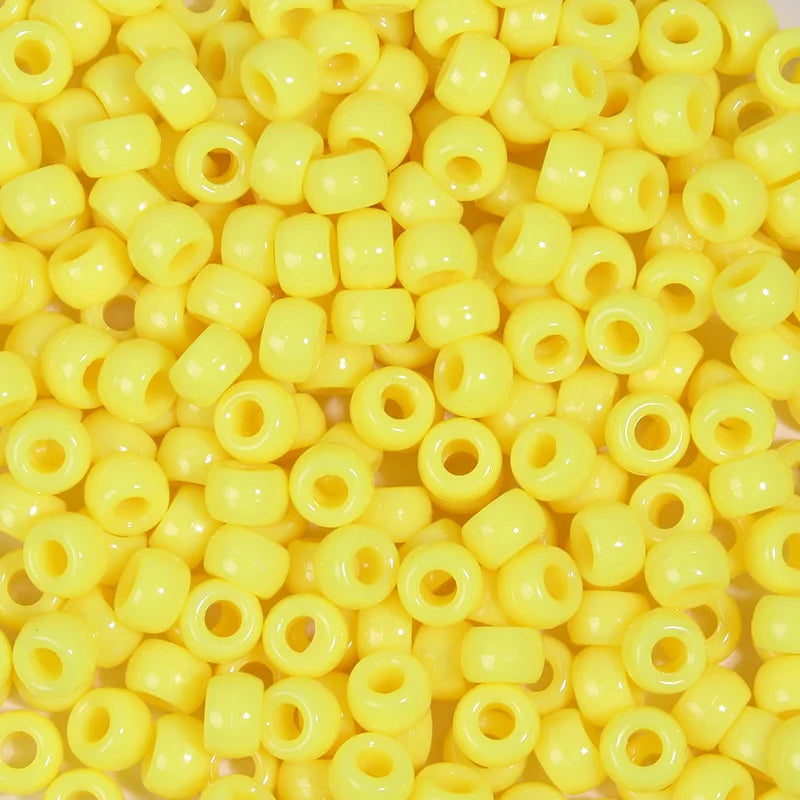 A pile of yellow rainbow pony beads for jewelry making and craft projects.