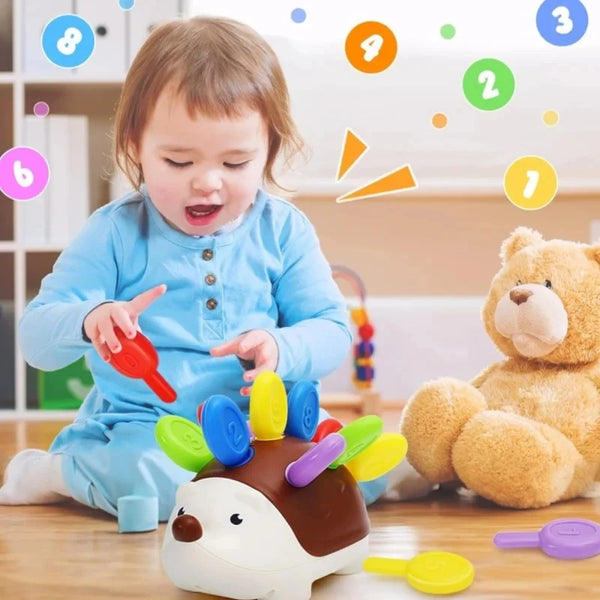 A toddler is interacting with a sensory hedgehog toy, surrounded by numbered colorful dots.