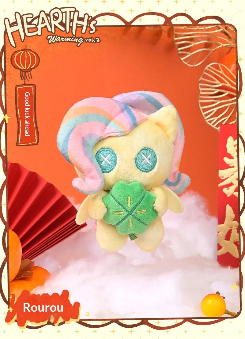 A fluffy, pastel-colored plush pendant featuring a unicorn-like face and a green gemstone, displayed against a white cloud ba