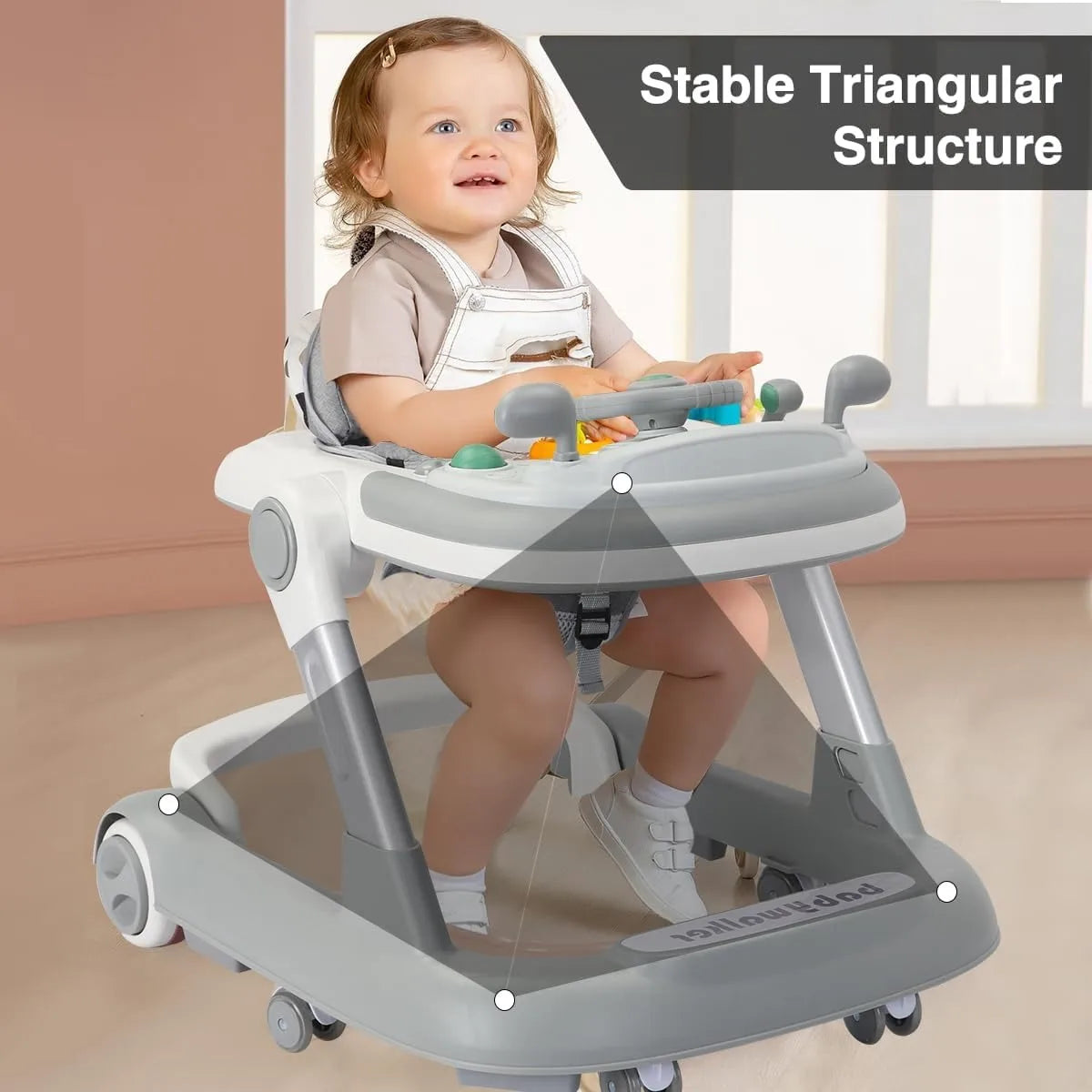 A baby is seated in a gray toddler push walker with a feeding tray, demonstrating its stable triangular structure.