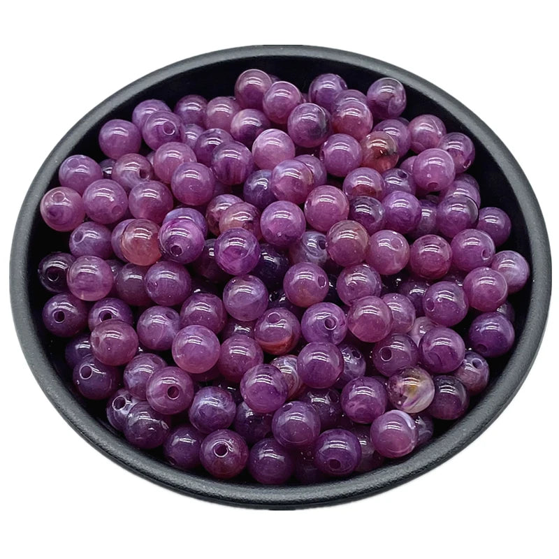 A bowl filled with small, round, purple acrylic beads for jewelry making.