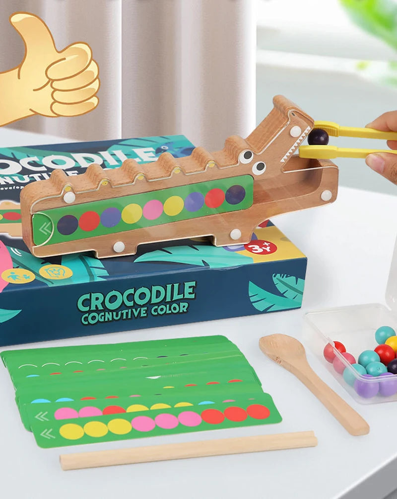 A wooden crocodile test tube clip toy with colorful beads and a yellow hand gesture, displayed on a box.