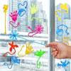 A hand is interacting with a set of colorful, stretchy, sticky climbing toys shaped like spiders and other creatures against 