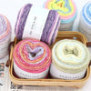 A collection of multicolored gradient yarn skeins in various shades and textures displayed in a wooden box.