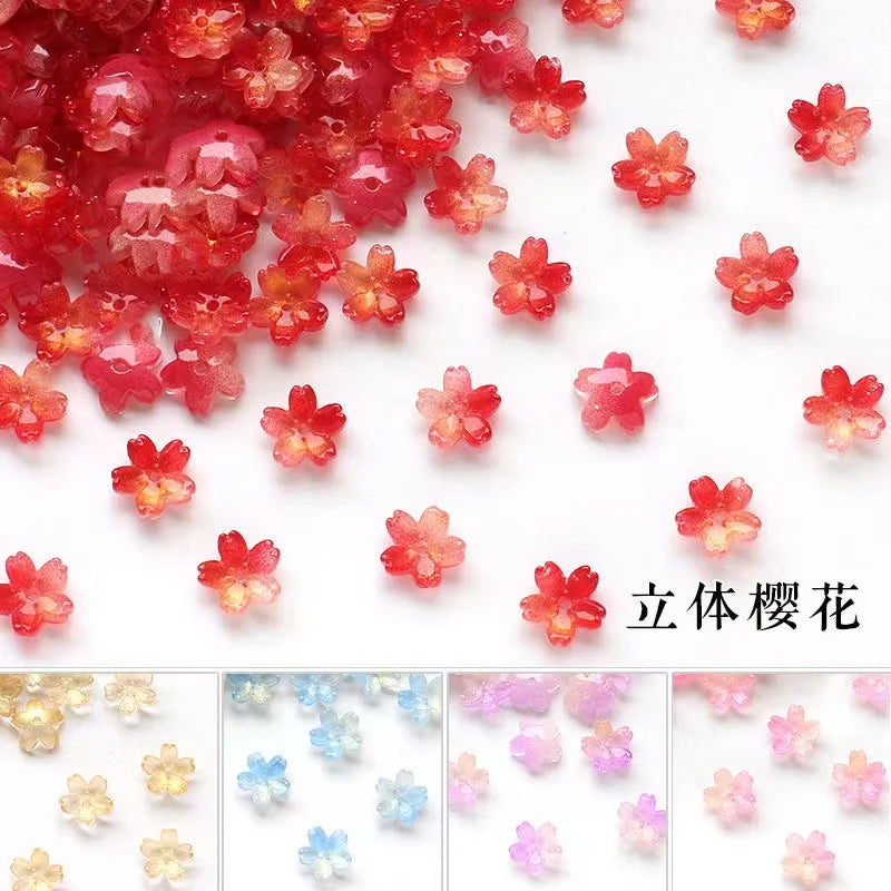 A pile of small, translucent red and pink sakura flower crystal glass beads for jewelry making.