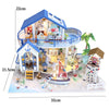 A miniature dollhouse kit of a seaside beach house with a balcony and interior decor on a white base.
