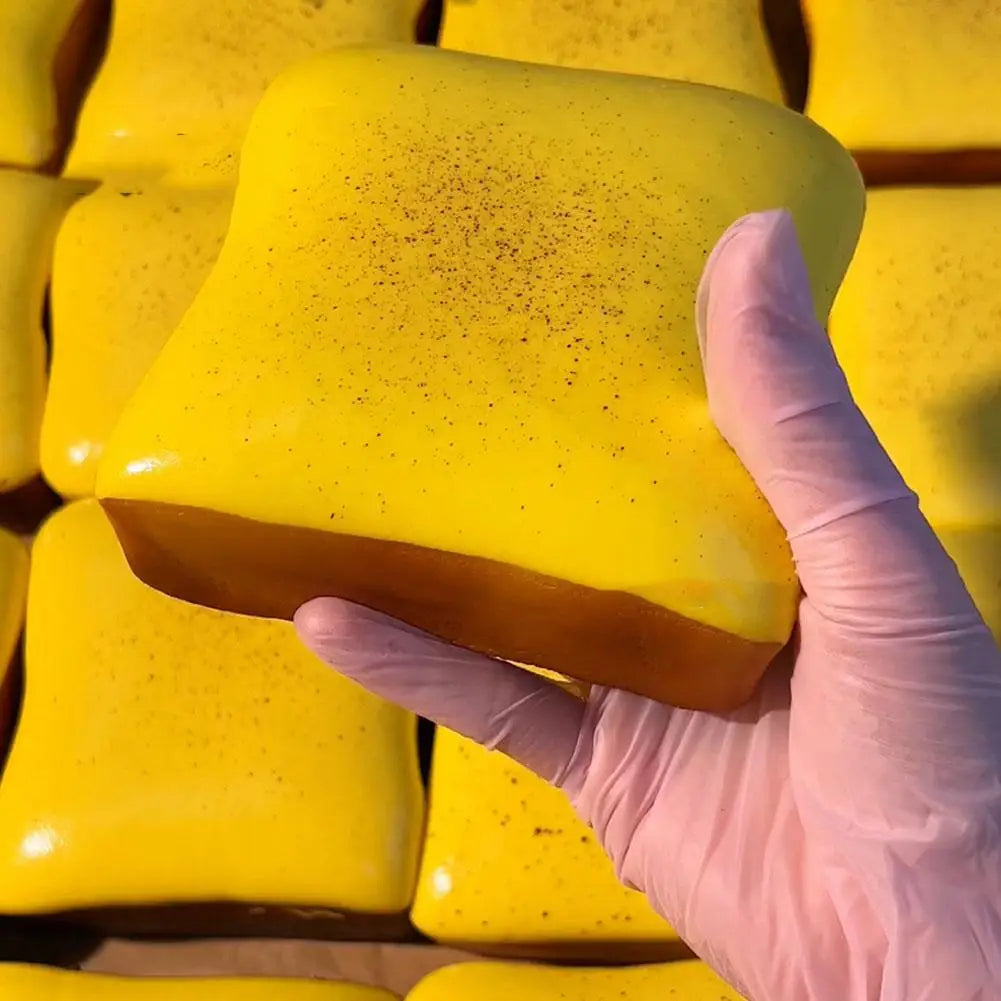 A hand in a pink glove holds a bright yellow squishy toast stress relief toy.