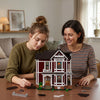 Two women examine a detailed miniature model of Halliwell Manor built from wooden blocks.