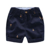 Navy blue boys cotton beach shorts featuring a gold anchor print and a matching button.