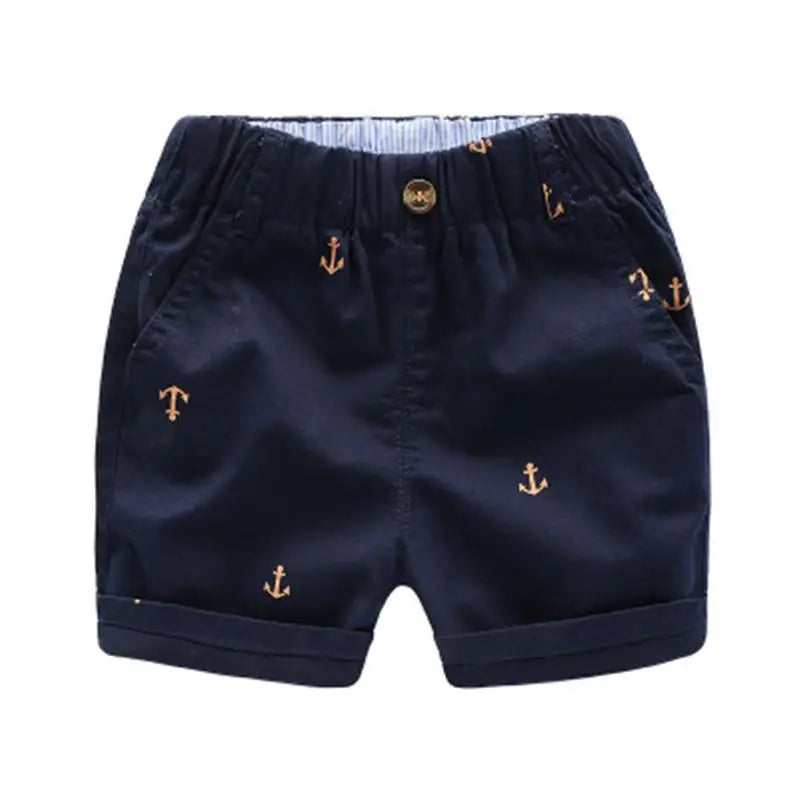 Navy blue boys cotton beach shorts featuring a gold anchor print and a matching button.