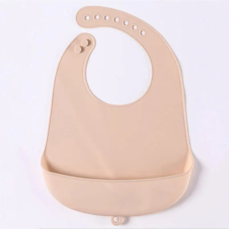 A light beige waterproof silicone baby bib with a catch pocket and multiple holes for fastening.