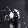 A silver metal fidget spinner resting on a dark, reflective surface.