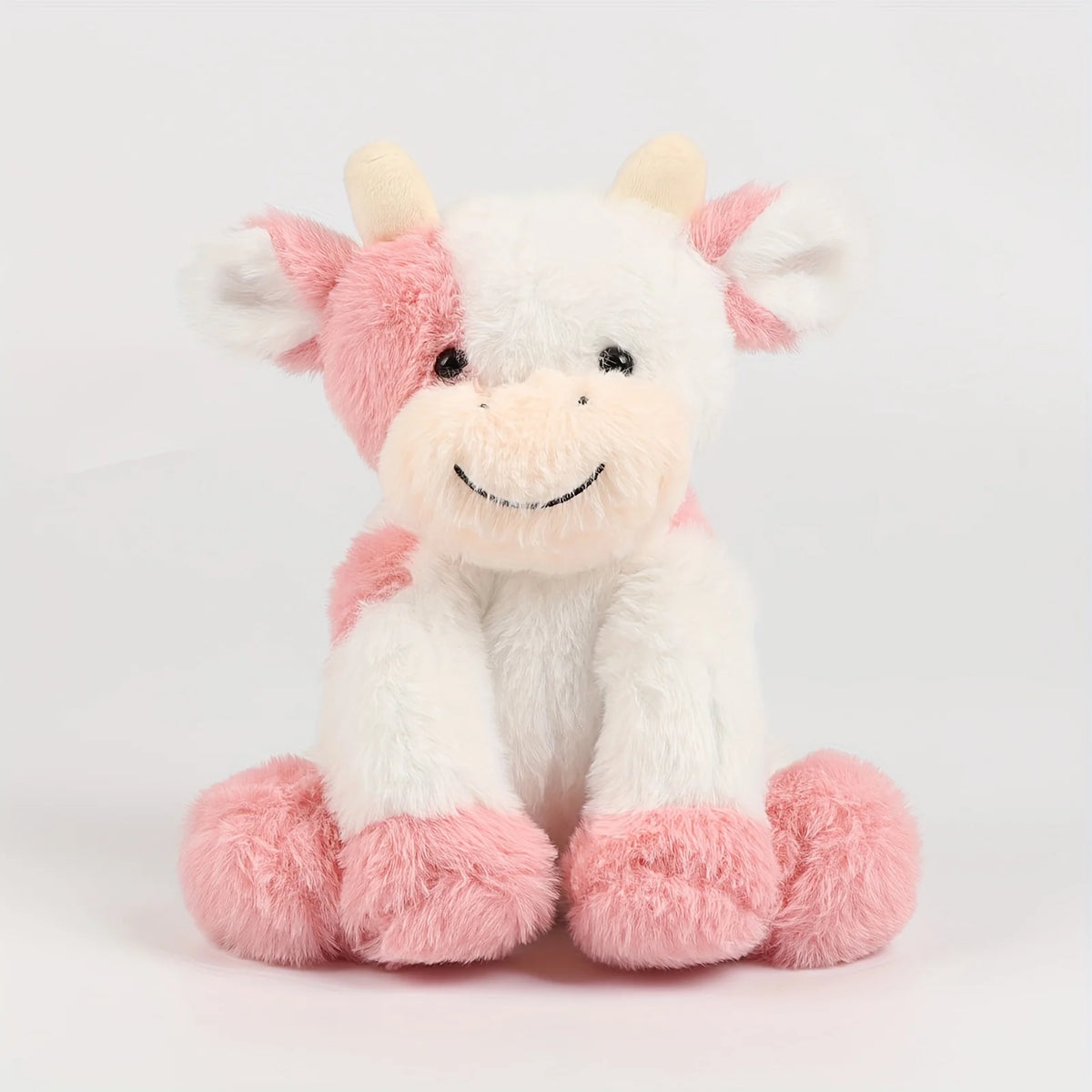 A soft, cuddly cow plush toy with white and pink fur, featuring a smiling face.