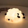 A glowing white silicone rabbit night light with closed eyes and small ears resting on a surface.