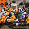 A collection of Halloween pumpkin rubber ducks in various colors and sizes displayed on a black mesh surface.