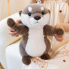 A soft, cuddly magnetic otter plush toy with brown and white fur is being held in a light-colored fabric.