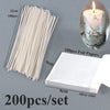 A set of 200 pieces of white foil paper candle wicks with metal sustainers shown next to a lit candle.