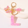 Gold initial heart keychain featuring a pink butterfly charm and pink tassel.
