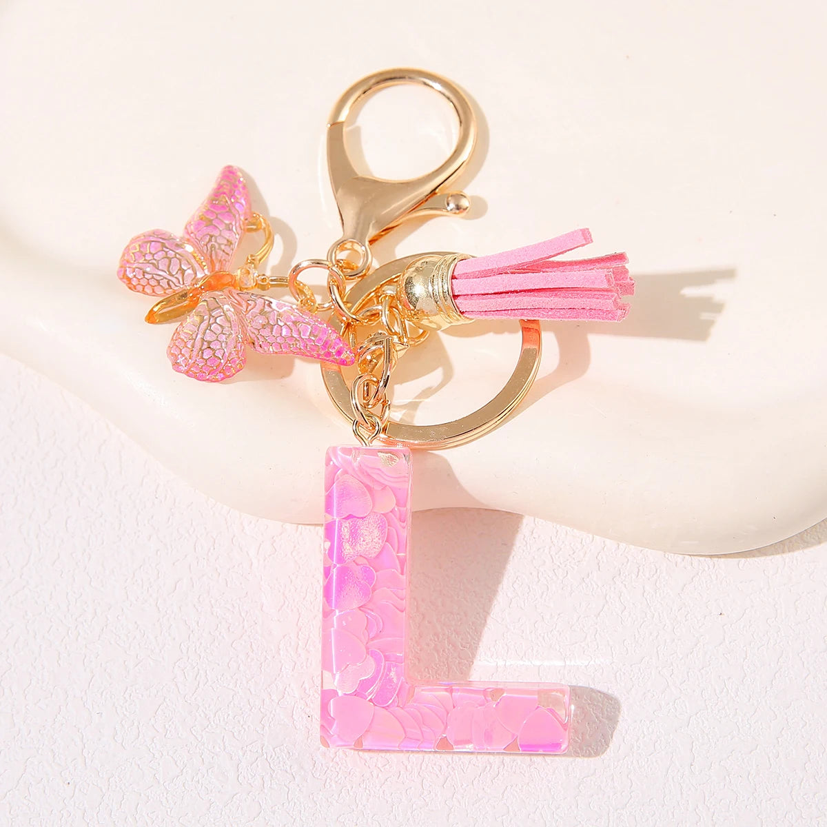 Gold initial heart keychain featuring a pink butterfly charm and pink tassel.