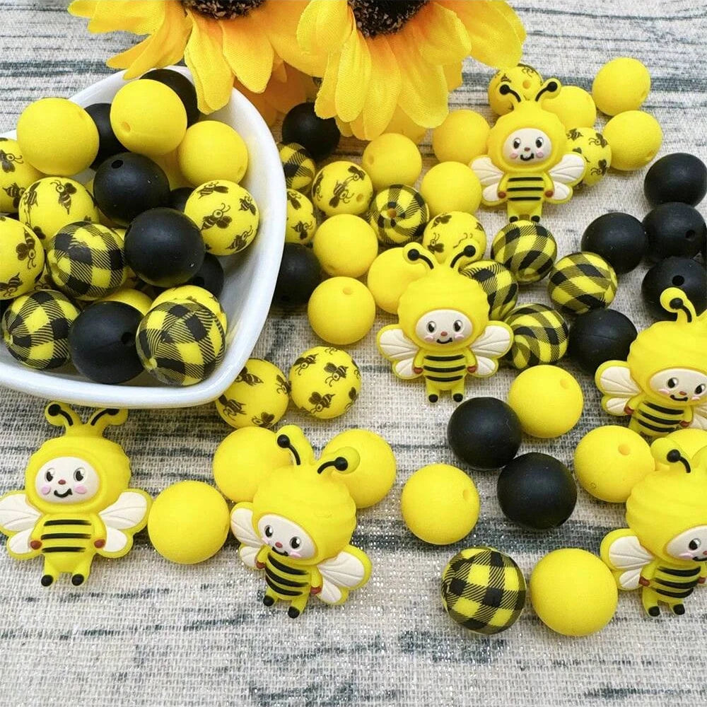 A collection of yellow and black silicone beads shaped like bees, including large flower-shaped beads.
