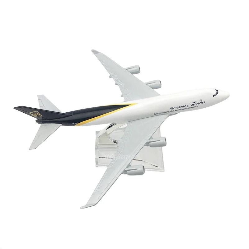 A white diecast model of a Boeing airplane with black and yellow accents, shown in flight.