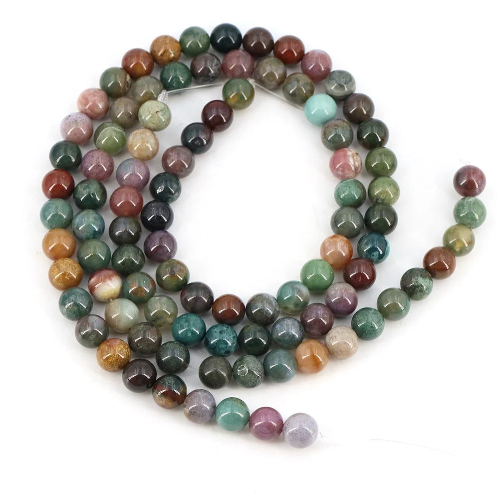 A strand of round loose natural India agate beads in various shades of green, brown, and purple stones.