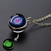 A pendant necklace featuring a glass sphere with a vibrant blue and purple galaxy design, next to a glowing green sphere.