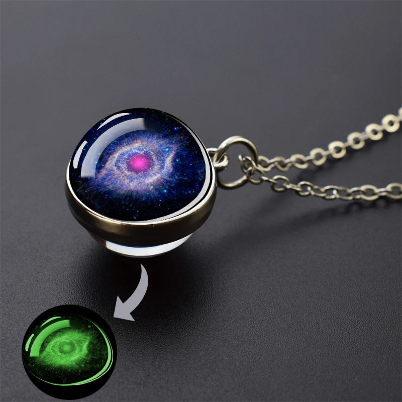 A pendant necklace featuring a glass sphere with a vibrant blue and purple galaxy design, next to a glowing green sphere.
