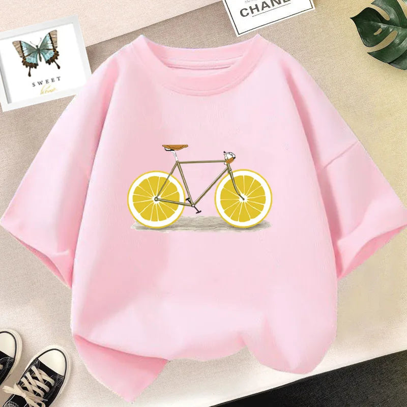 Pink graphic t-shirt featuring a bicycle decorated with sliced lemons and an avocado illustration