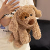 Un peluche de perro de osito marrón claro siendo sostenido por una persona.