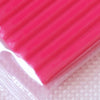 A close-up view of a bright pink, ridged polymer clay modeling material.