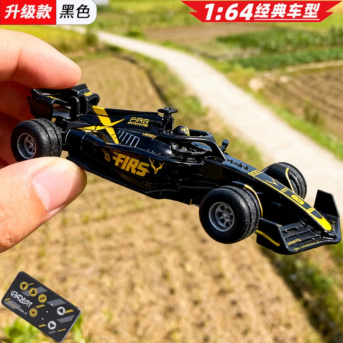 A black 1:64 scale alloy RC drift car is held by a hand, set against a blurred outdoor background.