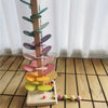 A wooden sensory music tree with a marble run featuring colorful, layered leaves.