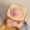 A pink plush pig stuffed animal with a light beige hood resting on a yellow tray.