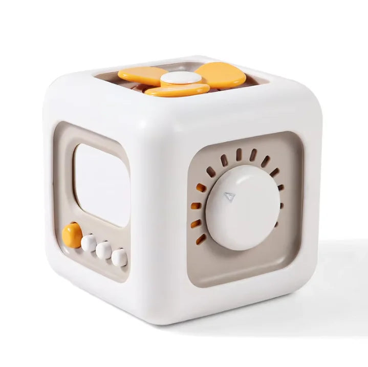 A white cube sensory toy with a transparent window and a round opening, containing several yellow and white discs.