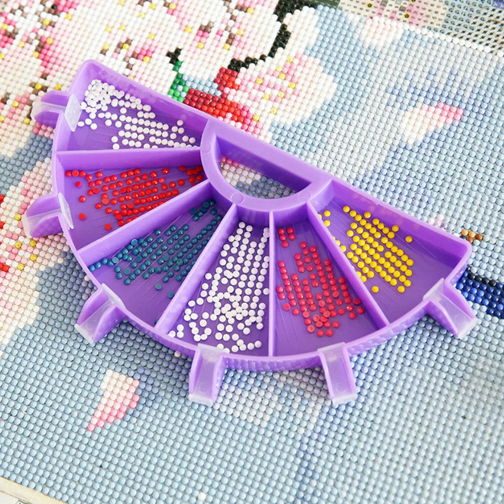 A purple diamond painting organizer tray with six compartments filled with colored sequins on a light blue background.