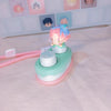 A collectible keycap blind box featuring a small figure with pink and blue hair on a light green base.