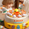 A round cake decorated with yellow and white duck figures, featuring the text B.DUCK AND FRIENDS.