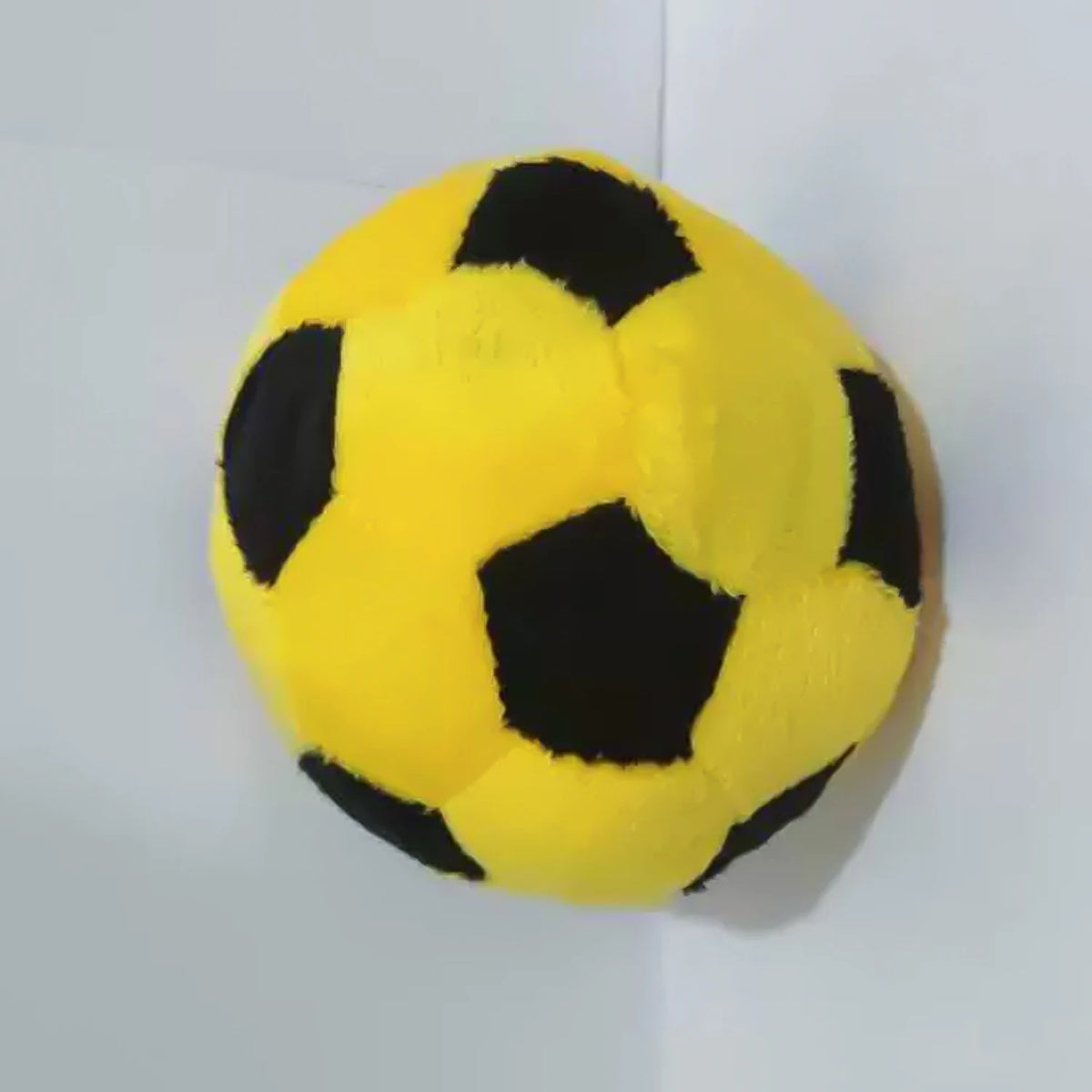A yellow and black soccer ball made of crochet fabric.