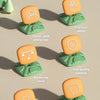 A set of five orange and green plastic game pieces illustrating different skills like practical ability, interaction, materia