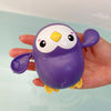 A purple and yellow bath time basketball hoop set for toddlers is held in a hand above water.
