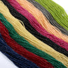 A close-up of multicolored faceted natural stone beads in various shades of red, green, black, and gold arranged in a diagona